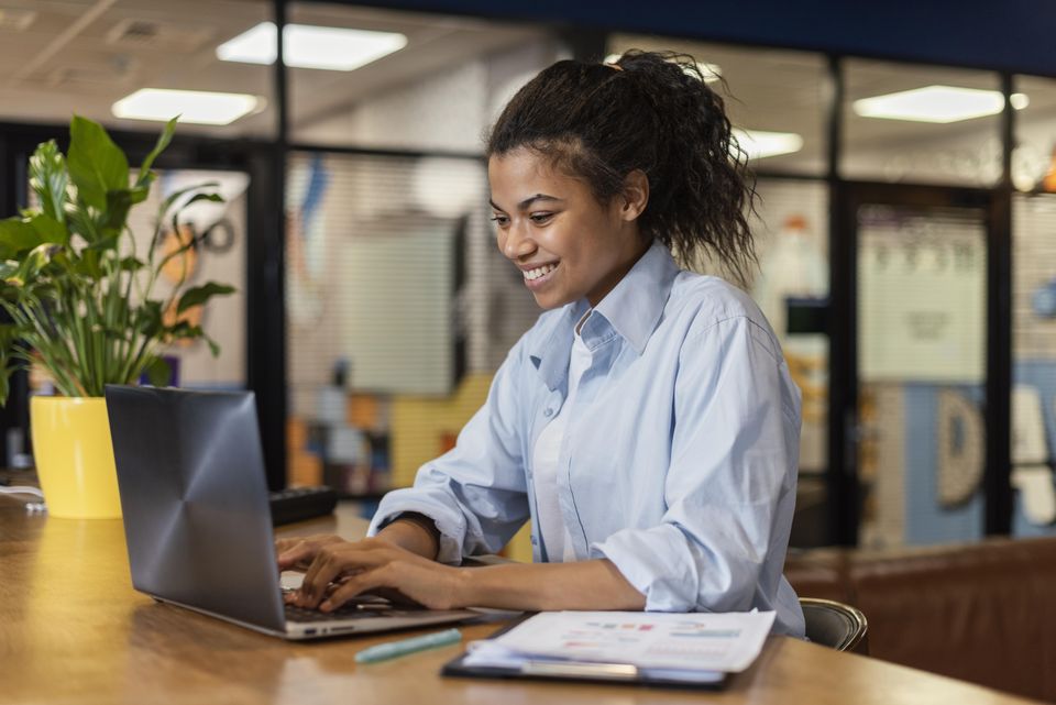 Mulher trabalhando em um laptop, consultando informações no escritório