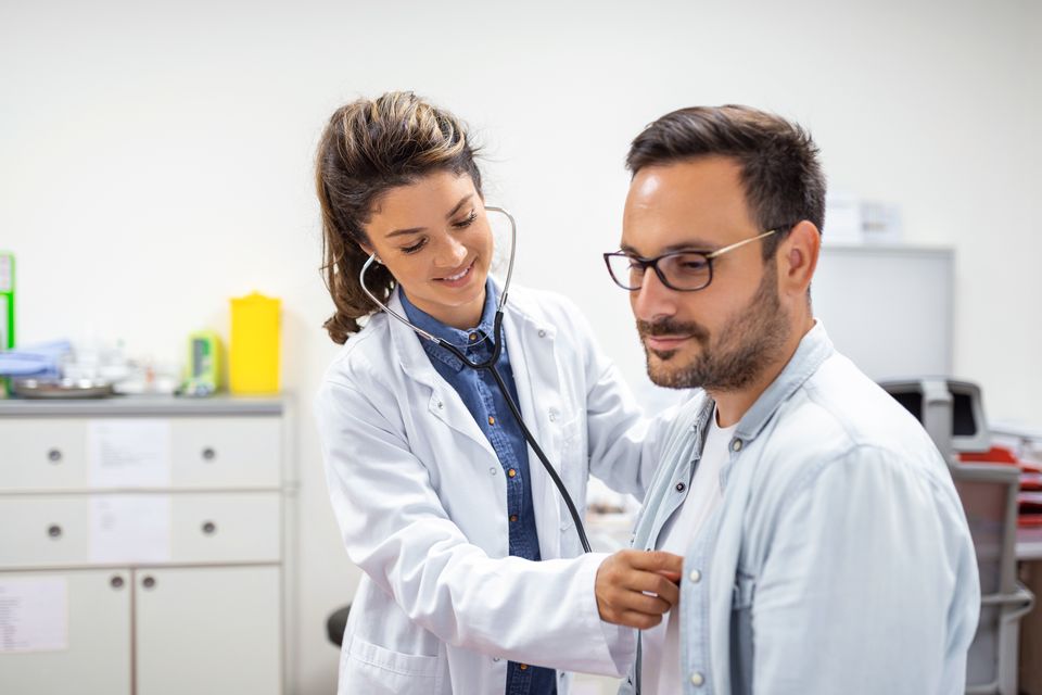 Médica de jaleco branco examinando um paciente com estetoscópio